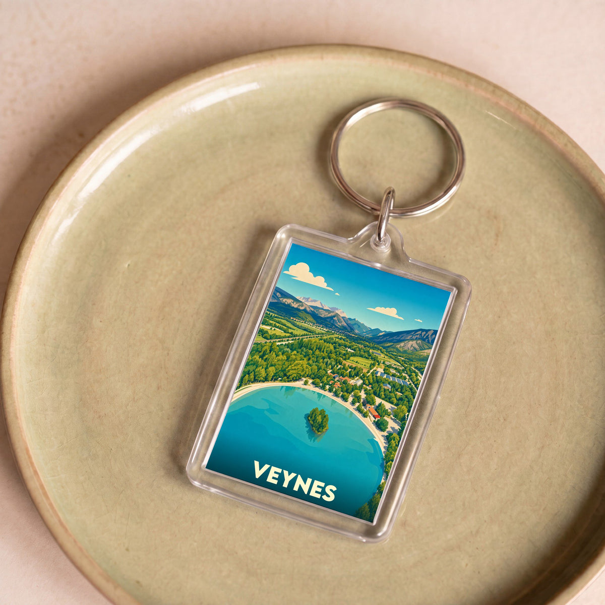 Porte-clés souvenir de la ville de Veynes avec une illustration stylisée d'un lac de montagne.