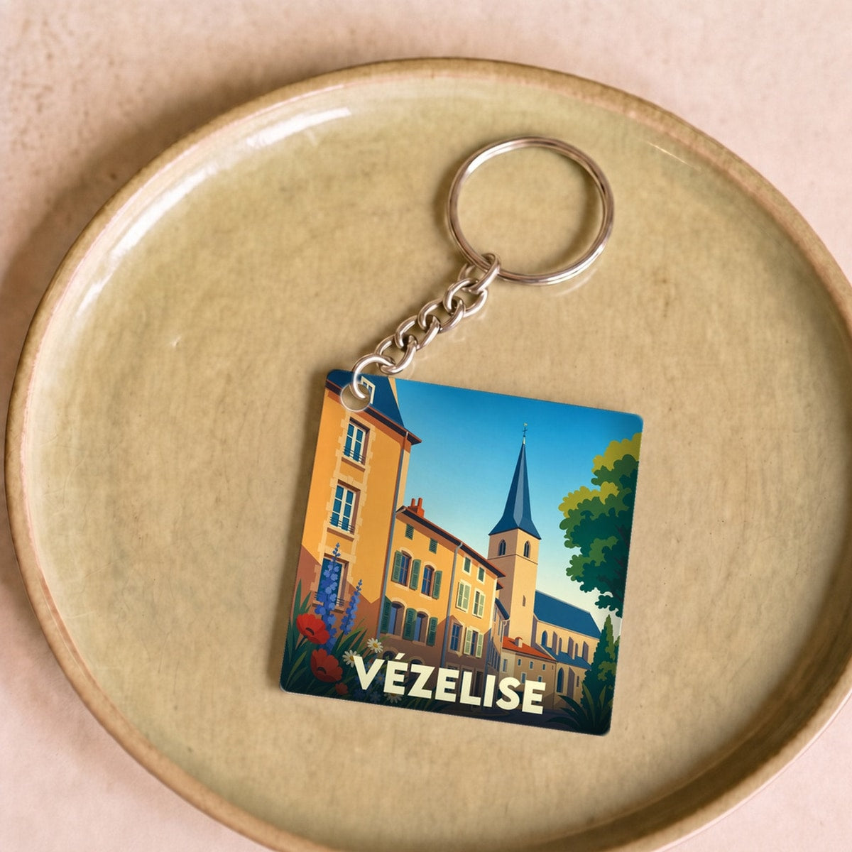 Porte-clés souvenir de la ville de Vézelise avec une illustration colorée et stylisée de ses façades et de son église.