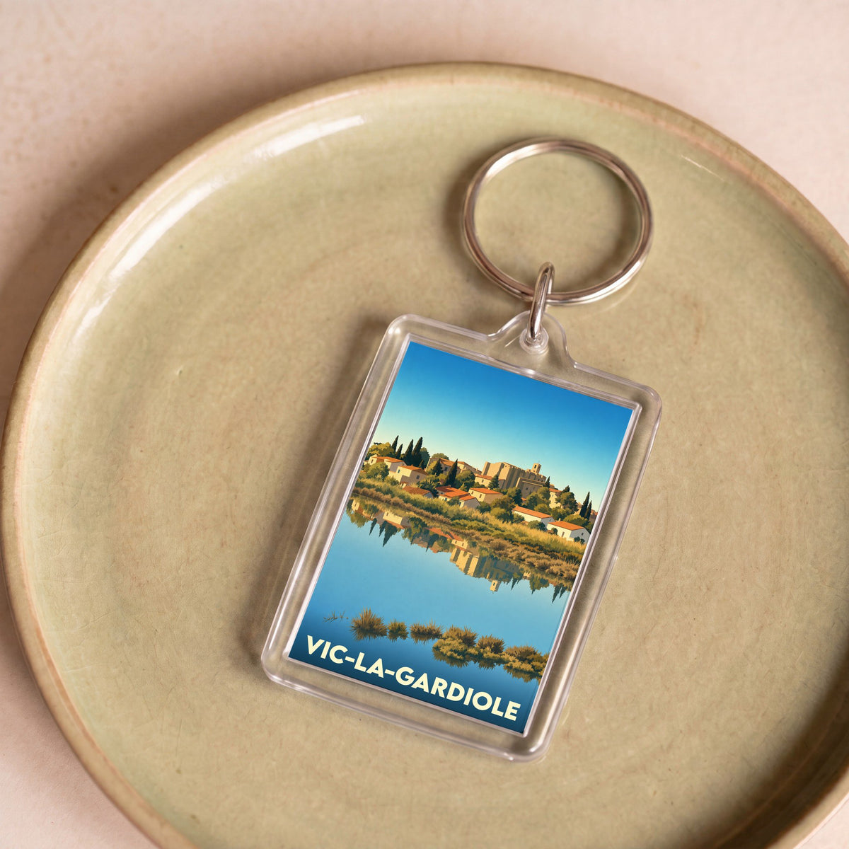 Porte-clés souvenir de la ville de Vic-la-Gardiole avec une illustration stylisée.