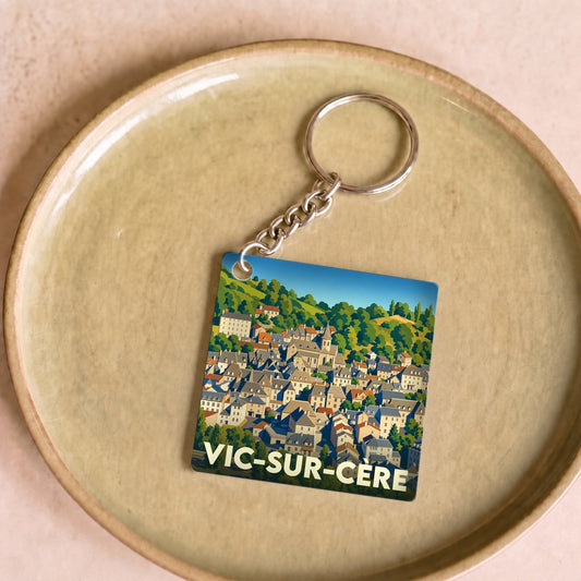 Porte-clés souvenir de la ville de Vic-sur-Cère avec une illustration stylisée.