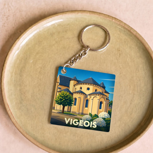 Porte-clés souvenir de la ville de Vigeois avec une illustration stylisée de son église abbatiale.