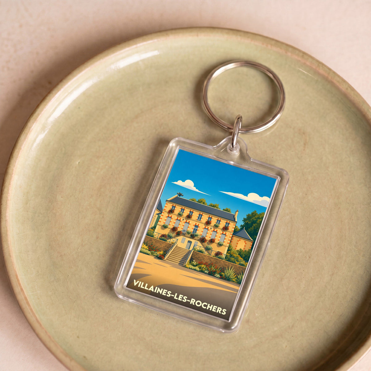Porte-clés souvenir de la ville de Villaines-les-Rochers avec une illustration colorée et stylisée.