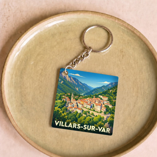 Porte-clés souvenir de la ville de Villars-sur-Var avec une illustration stylisée du village et des montagnes.