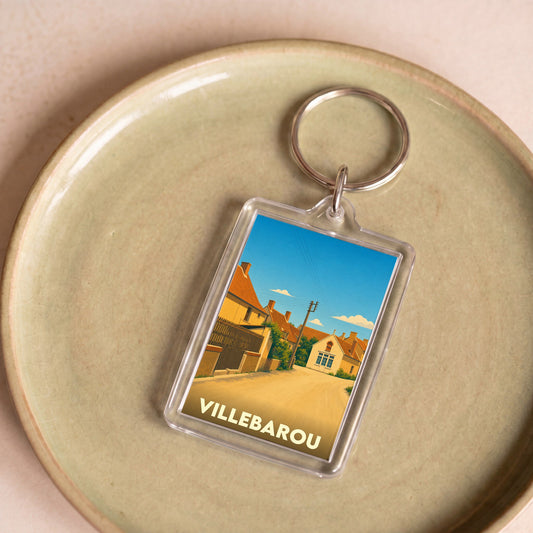 Porte-clés souvenir de la ville de Villebarou avec une illustration stylisée d'une rue ensoleillée.