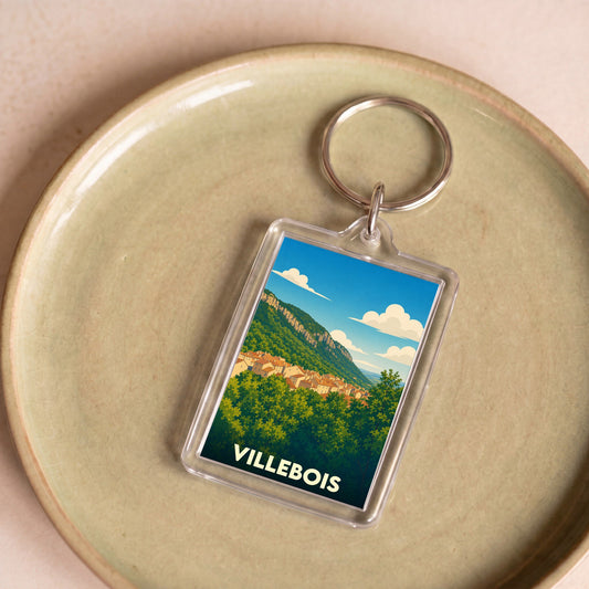 Porte-clés souvenir de la ville de Villebois avec une illustration paysagère stylisée.