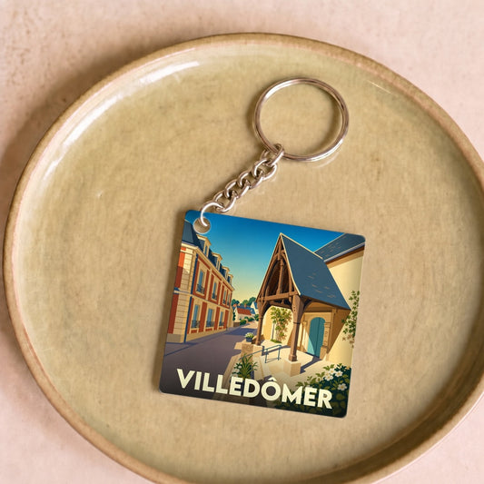 Porte-clés souvenir de la ville de Villedômer avec une illustration stylisée.