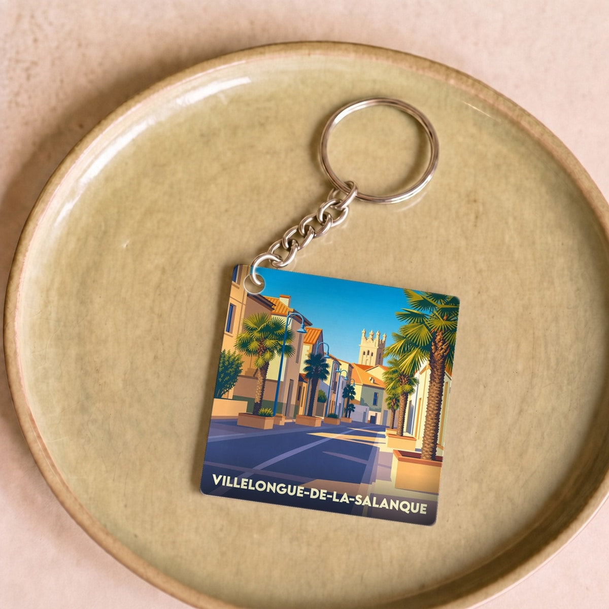 Porte-clés souvenir de Villelongue-de-la-Salanque avec une illustration stylisée et colorée de la ville.