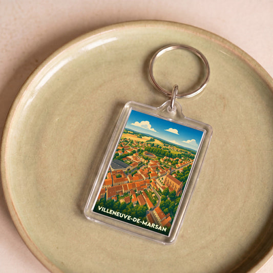 Porte-clés souvenir de la ville de Villeneuve-de-Marsan avec une illustration aérienne colorée et stylisée.