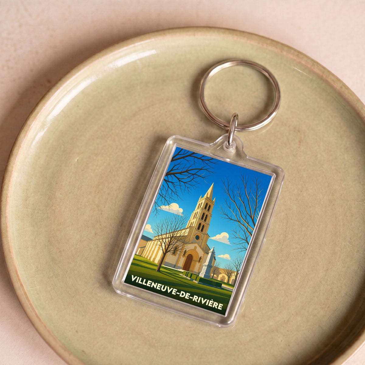 Porte-clés souvenir de la ville de Villeneuve-de-Rivière avec une illustration stylisée de son église.