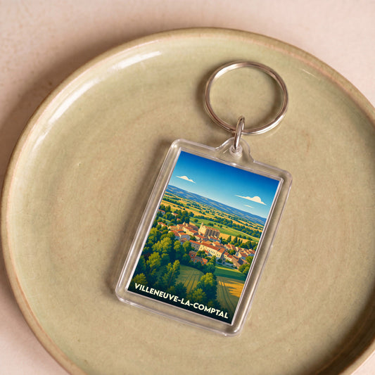 Porte-clés souvenir de la ville de Villeneuve-la-Comptal avec une illustration stylisée.