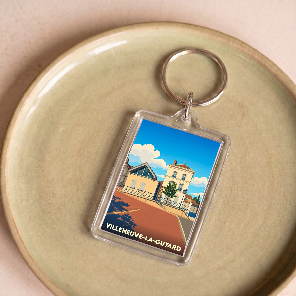 Porte-clés souvenir de la ville de Villeneuve-la-Guyard avec une illustration stylisée.