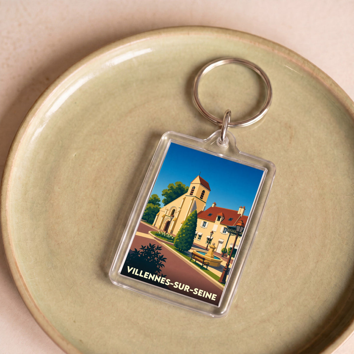 Porte-clés souvenir de la ville de Villennes-sur-Seine avec une illustration stylisée de son église et d'une place.