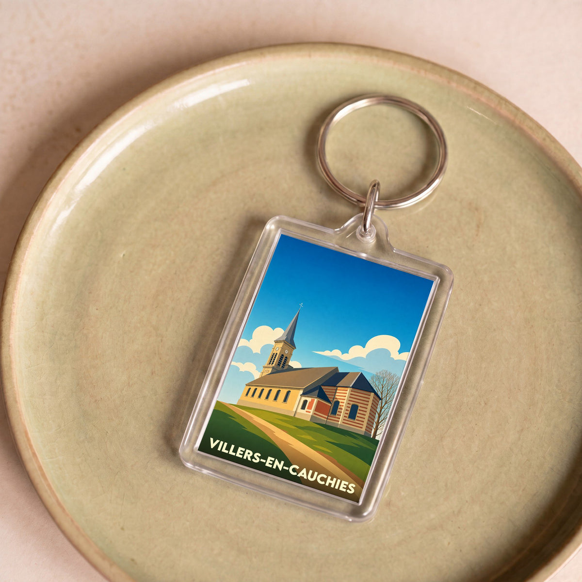 Porte-clés souvenir de la ville de Villers-en-Cauchies avec une illustration stylisée.