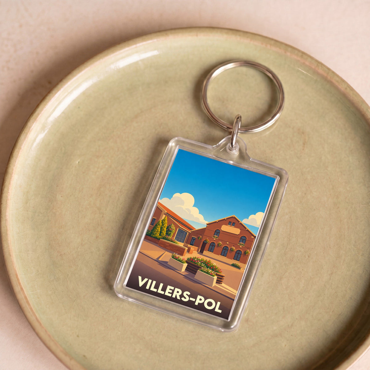Porte-clés souvenir de la ville de Villers-Pol avec une illustration stylisée d'un bâtiment en briques.