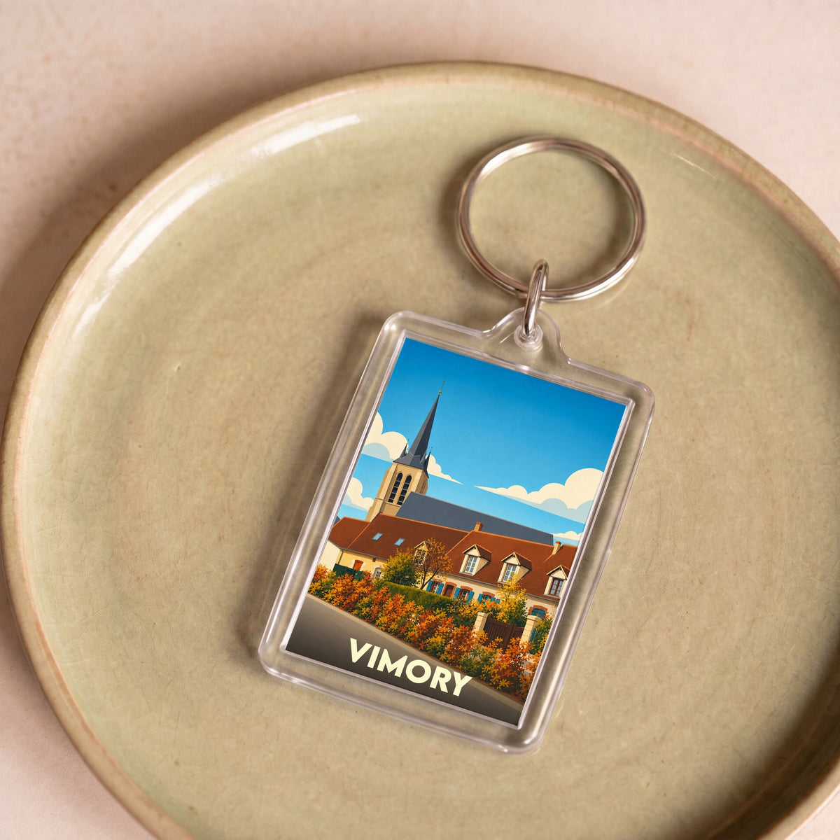 Porte-clés souvenir de la ville de Vimory avec une illustration stylisée d'une église et de maisons.