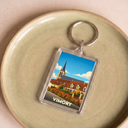 Porte-clés souvenir de la ville de Vimory avec une illustration stylisée d'une église et de maisons.