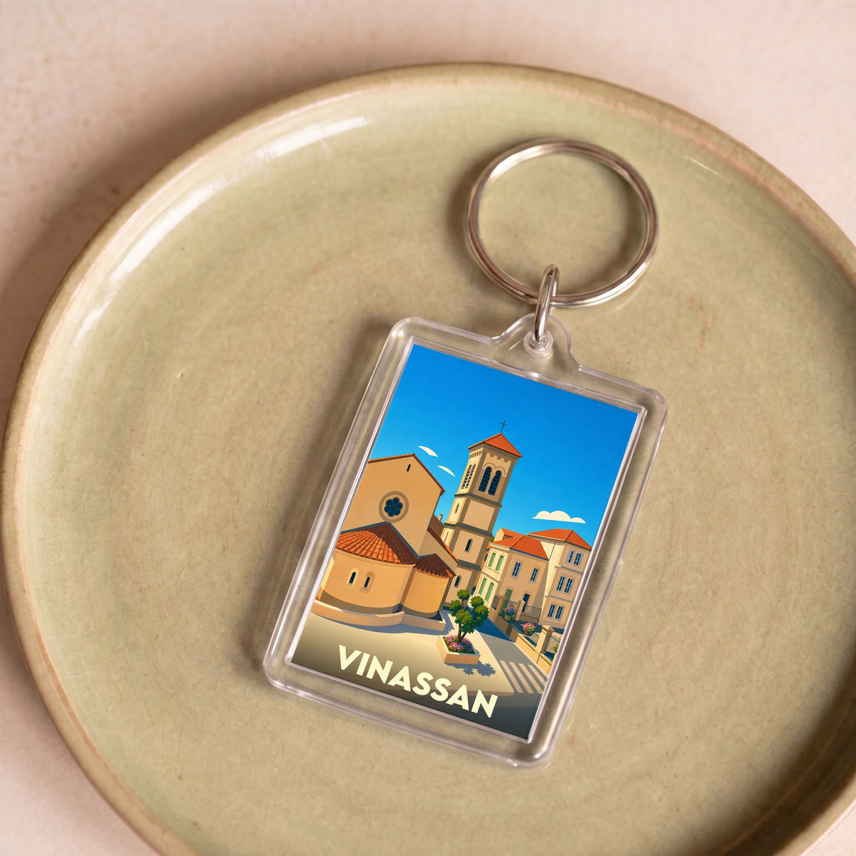 Porte-clés souvenir de la ville de Vinassan avec une illustration stylisée.