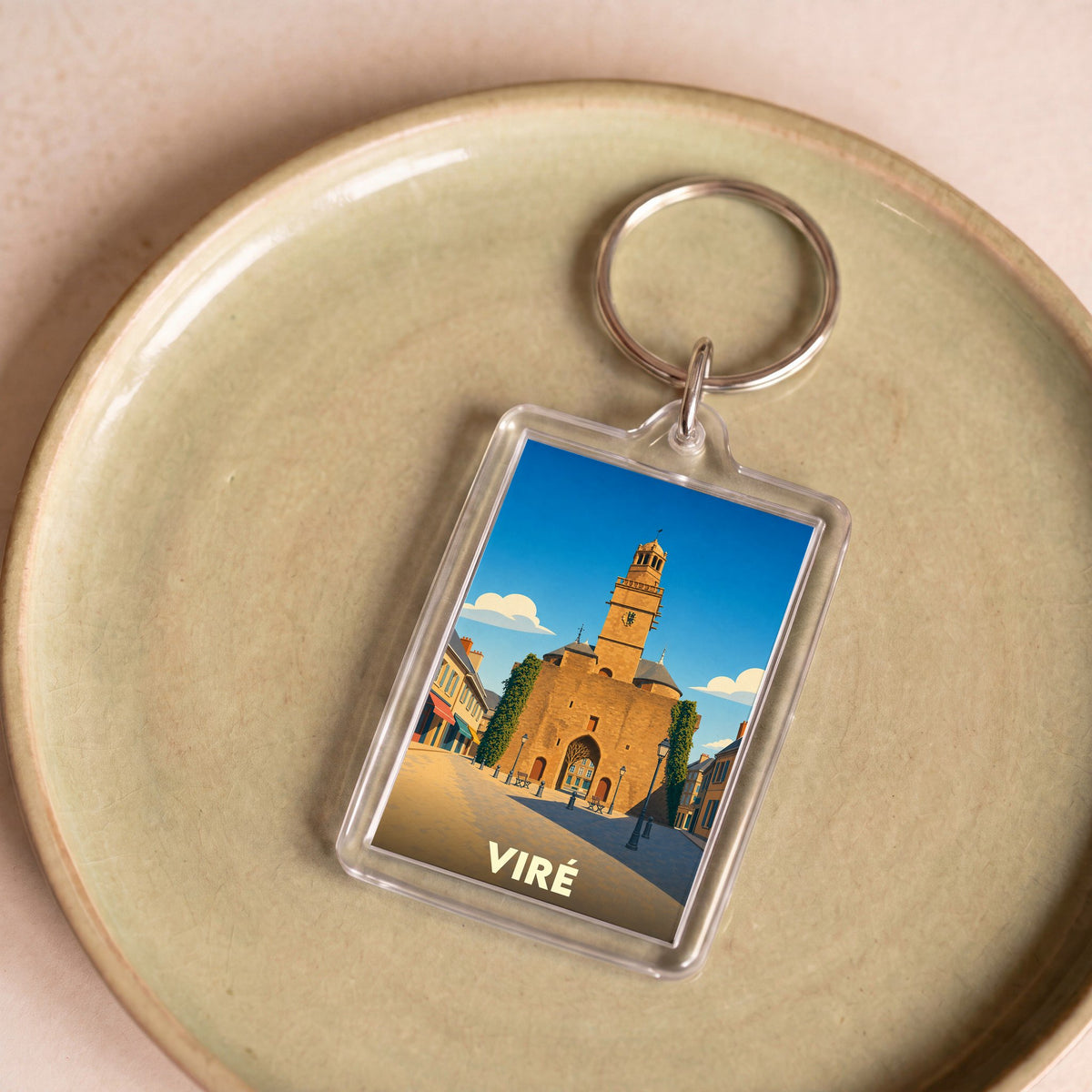 Porte-clés souvenir de la ville de Viré avec une illustration stylisée d'un monument historique sous un ciel bleu.