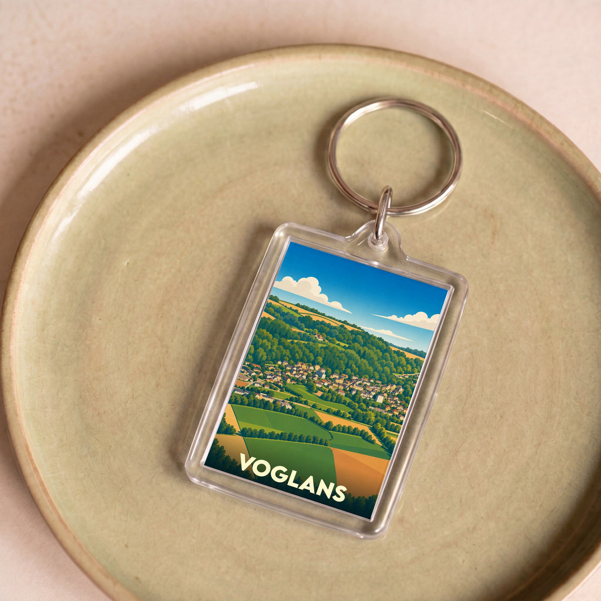 Porte-clés souvenir de la ville de Voglans avec une illustration paysagère stylisée.