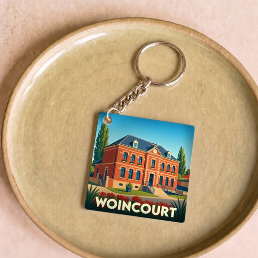 Porte-clés souvenir de la ville de Woincourt avec une illustration stylisée de sa mairie.