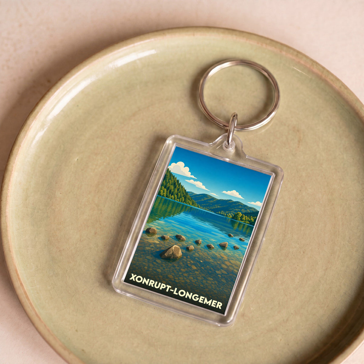 Porte-clés souvenir de la ville de Xonrupt-Longemer avec une illustration stylisée d'un lac de montagne.