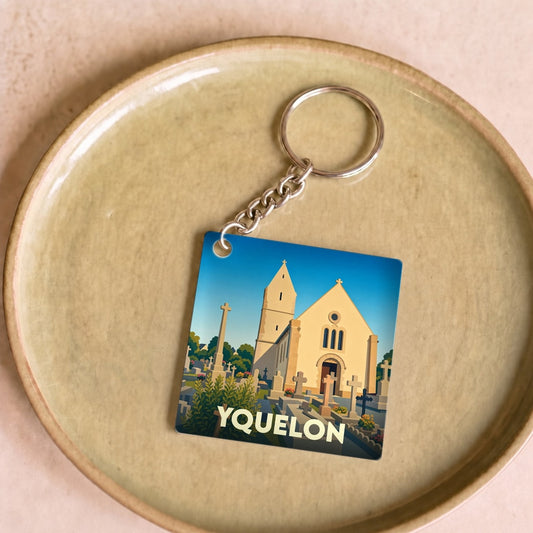 Porte-clés souvenir de la ville d'Yquelon avec une illustration stylisée d'une église et de son cimetière.