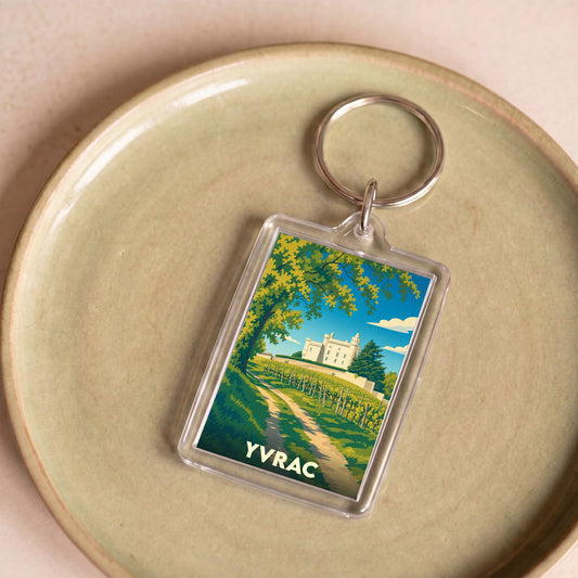 Porte-clés souvenir de la ville d'Yvrac avec une illustration stylisée d'un château et de vignobles.
