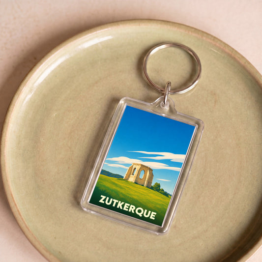 Porte-clés souvenir de la ville de Zutkerque avec une illustration stylisée de ruines historiques.