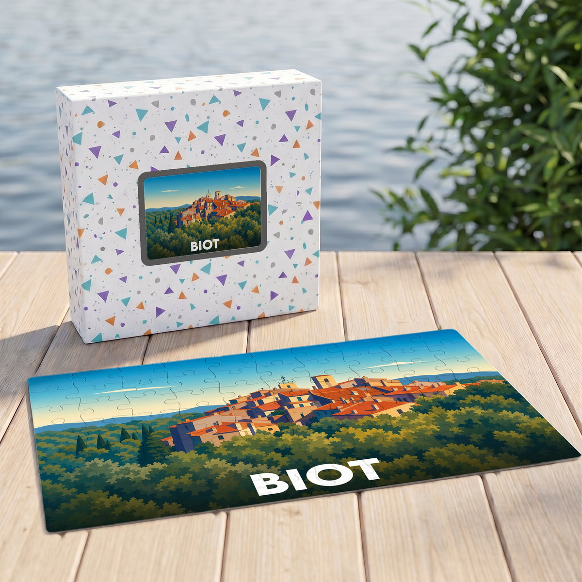 Puzzle souvenir de la ville de Biot présentant une illustration stylisée d'un village perché au milieu de la verdure.