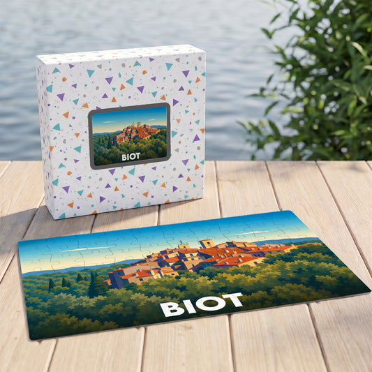 Puzzle souvenir de la ville de Biot présentant une illustration stylisée d'un village perché au milieu de la verdure.