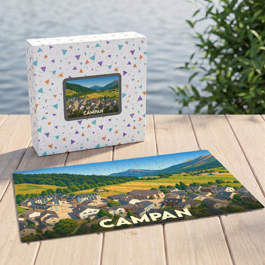 Puzzle souvenir de la ville de Campan avec une illustration stylisée d'un paysage montagneux et de ses habitations.