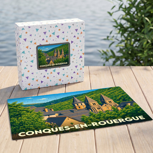 Puzzle souvenir de la ville de Conques-en-Rouergue avec une illustration stylisée de son abbaye et de son paysage vallonné.