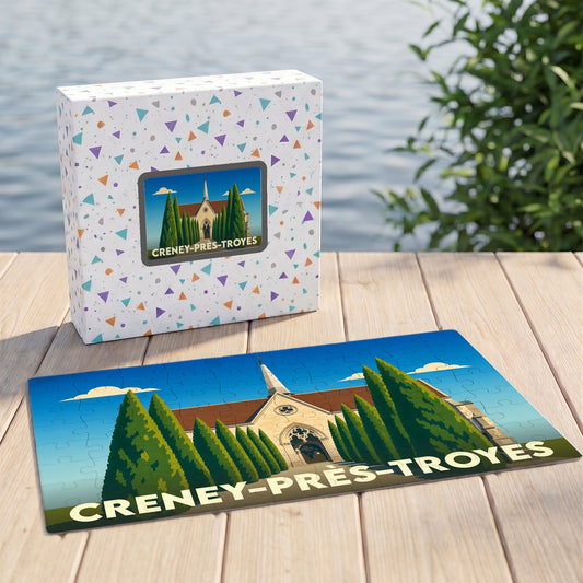 Puzzle souvenir de Creney-près-Troyes présentant une illustration stylisée de son église entourée de cyprès.