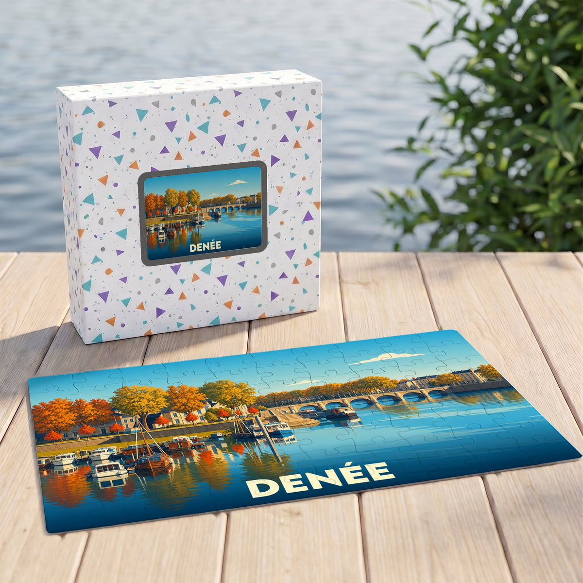 Puzzle souvenir de la ville de Denée avec une illustration stylisée d'un bord de rivière automnal.