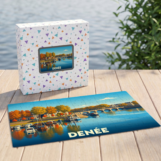 Puzzle souvenir de la ville de Denée avec une illustration stylisée d'un bord de rivière automnal.