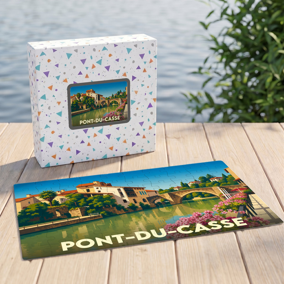 Puzzle souvenir de la ville de Pont-du-Casse avec une illustration colorée représentant un pont et des bâtiments en bord d'eau.