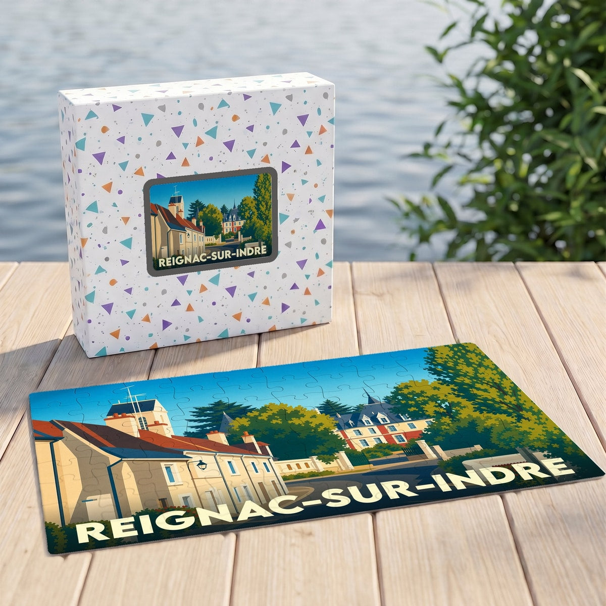Puzzle souvenir de la ville de Reignac-sur-Indre avec son coffret assorti, présentant une illustration stylisée du village.