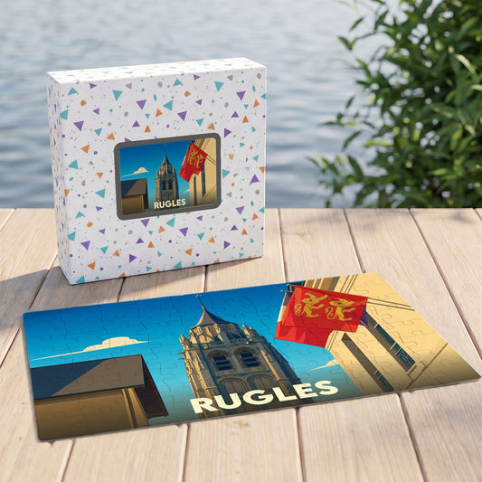 Puzzle souvenir de la ville de Rugles avec une illustration stylisée de son église et de drapeaux normands.