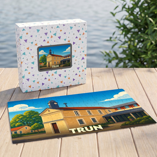 Puzzle souvenir de la ville de Trun avec une illustration stylisée de son patrimoine, présenté à côté de sa boîte.