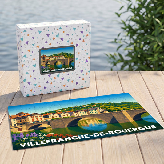 Puzzle souvenir de la ville de Villefranche-de-Rouergue avec une illustration stylisée de son pont et ses maisons en bord de rivière.