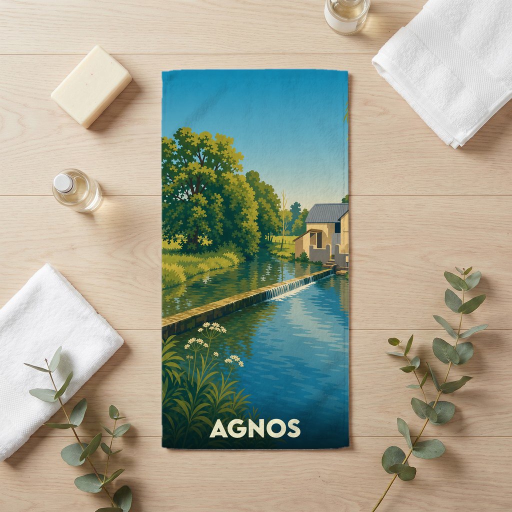 Serviette de bain souvenir de la ville d'Agnos avec une illustration stylisée d'un moulin au bord de l'eau.