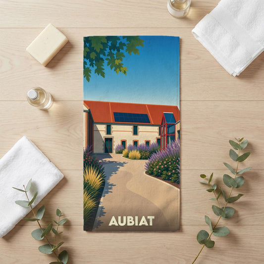 Serviette de bain souvenir de la ville d'Aubiat avec une illustration stylisée d'un bâtiment et de jardins.