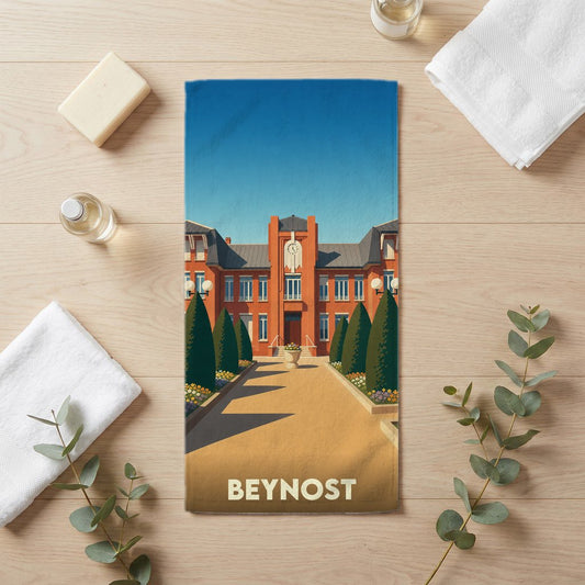 Serviette de bain souvenir de la ville de Beynost illustrée d'un bâtiment en briques rouges et de jardins.