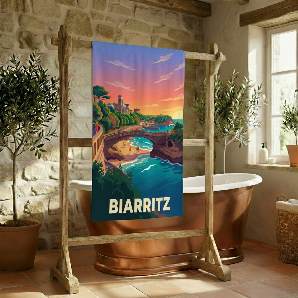 Serviette de bain souvenir de la ville de Biarritz avec une illustration stylisée de son paysage côtier au coucher du soleil.