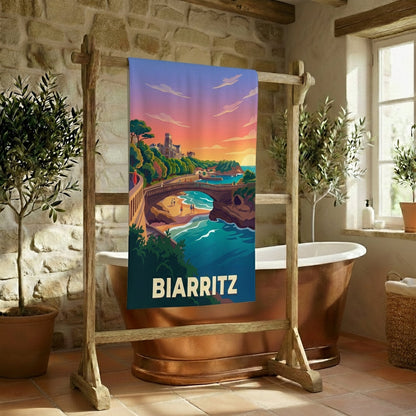 Serviette de bain souvenir de la ville de Biarritz avec une illustration stylisée de son paysage côtier au coucher du soleil.