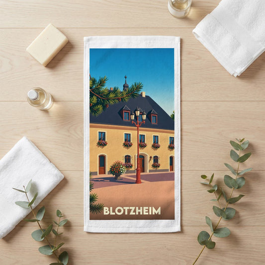 Serviette de bain souvenir de la ville de Blotzheim avec une illustration stylisée d'un bâtiment traditionnel.