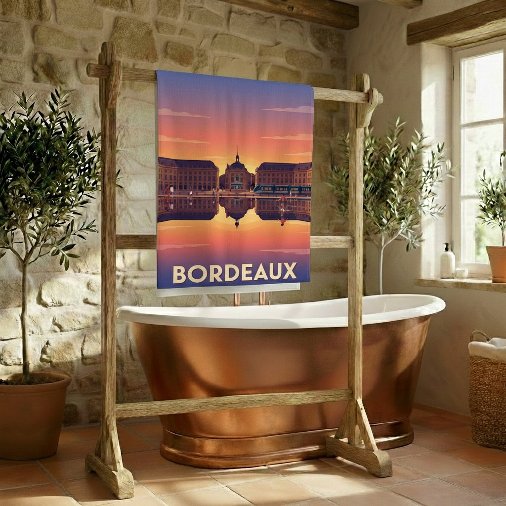 Serviette de bain souvenir de la ville de Bordeaux avec une illustration stylisée de la Place de la Bourse au coucher du soleil.