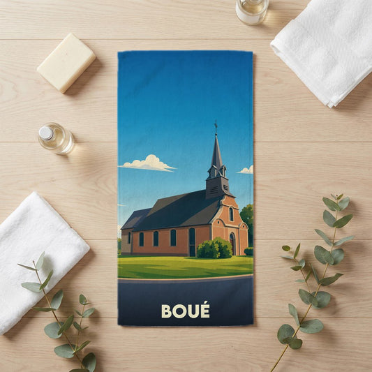 Serviette de bain souvenir de la ville de Boué illustrée d'une église stylisée sous un ciel bleu.