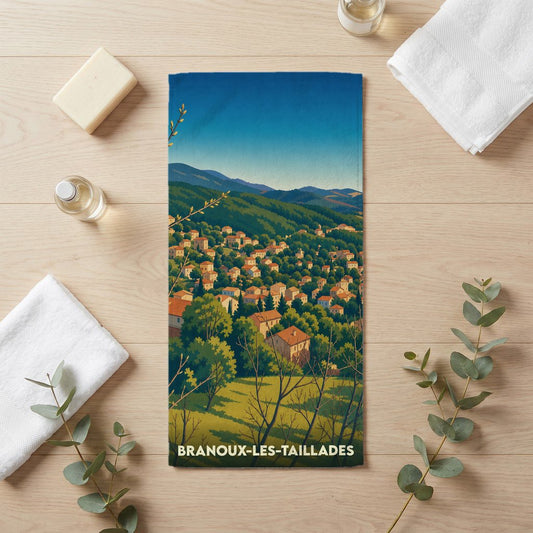 Serviette de bain souvenir de Branoux-les-Taillades avec une illustration stylisée d'un village de montagne.