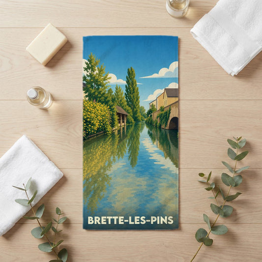 Serviette de bain souvenir de la ville de Brette-les-Pins avec une illustration stylisée d'un canal verdoyant.